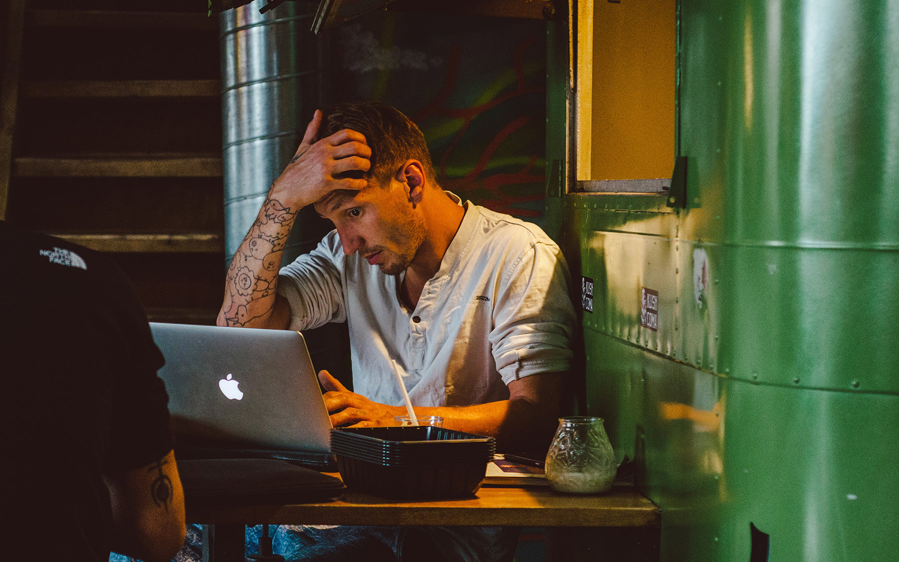 A stressful Danish man straining his eyes while working with a MacBook.