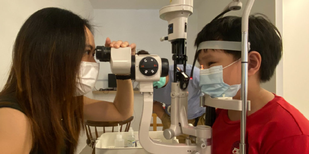 An optometrist performing comprehensive eye examination to a kid.