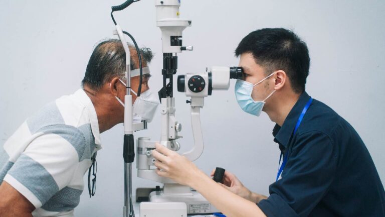 An optometrist performs comprehensive eye examination with a slit lamp to an old man