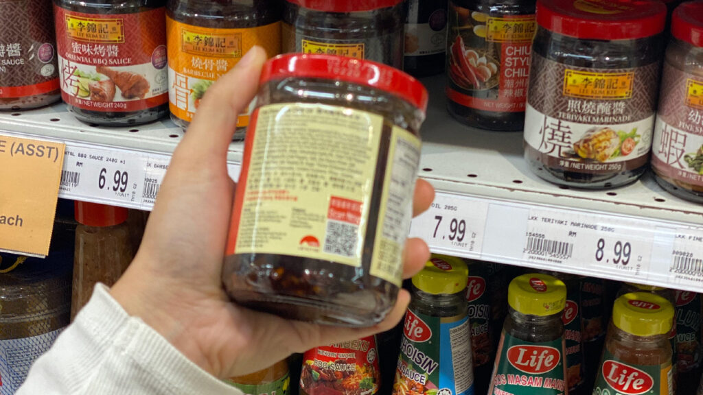 A person is checking the ingredients label of a hot sauce in the supermarket.