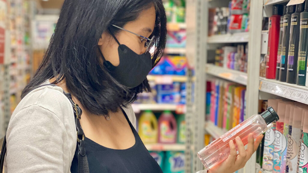 A working lady checking hair shampoo labels in the supermarket.